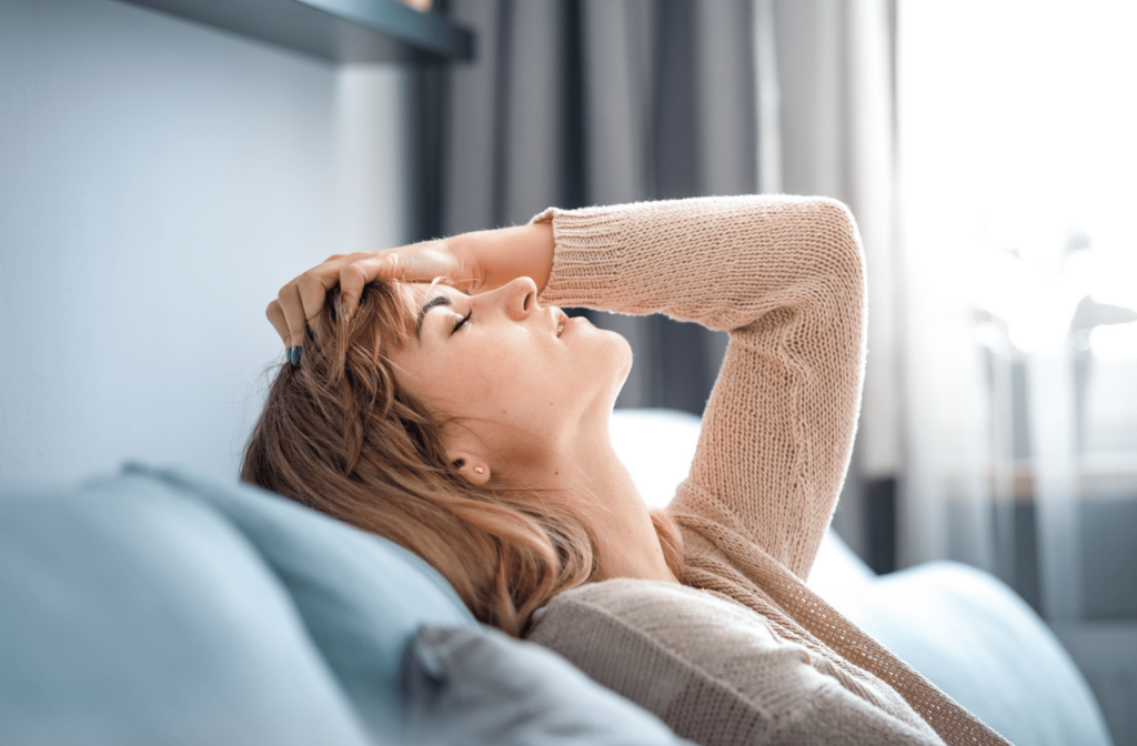 Exhausted woman sitting on the couch with her head back due to caregiver fatigue